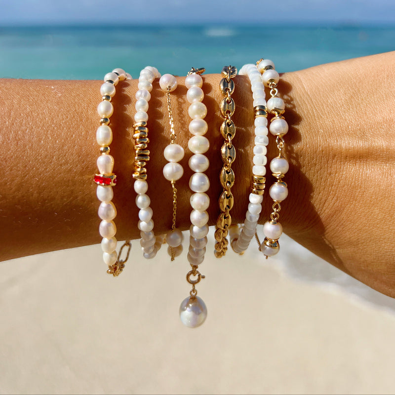 Pearl bracelets on a wrist with a beach background